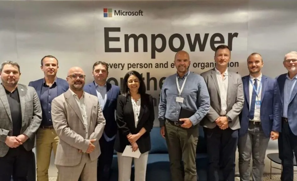 Group photo from a Microsoft partner roundtable, in front of a wall reading Empower every person and every organization.
